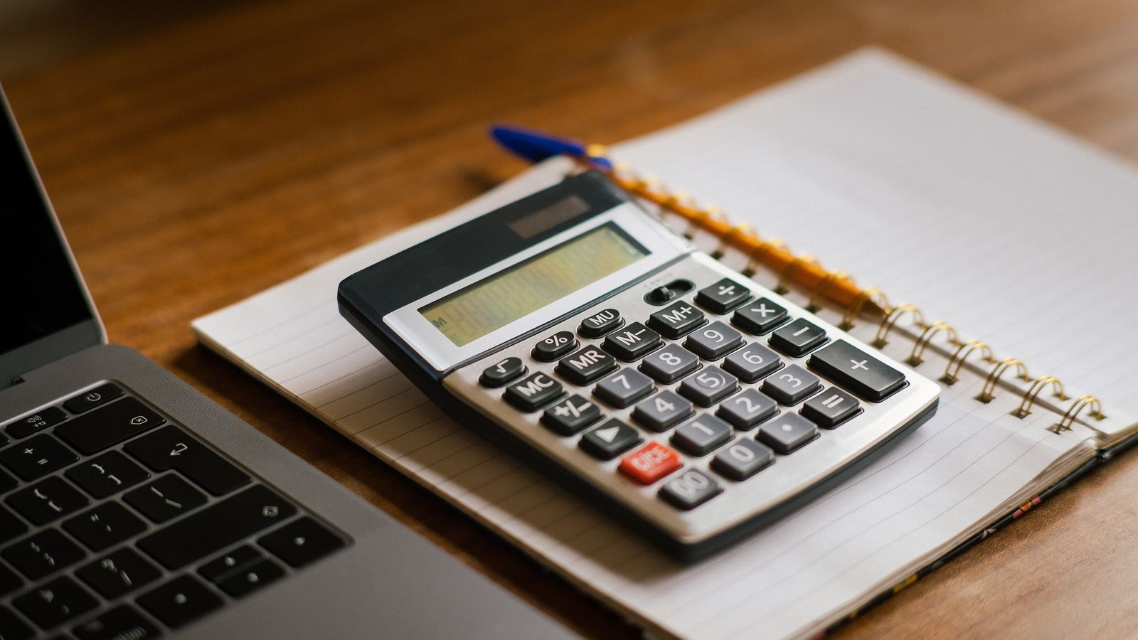 A calculator, glasses, and cash on an accountant's desk