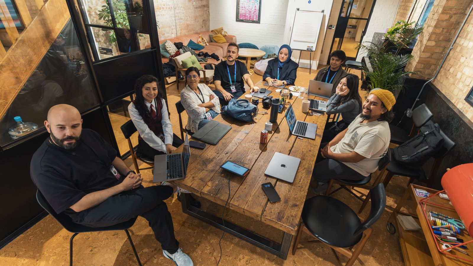A diverse team collaborating around a table with laptops in a modern office