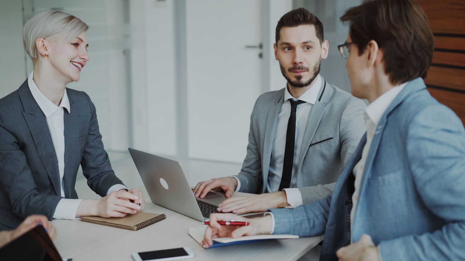 A marketing agency team in a strategy meeting around a laptop